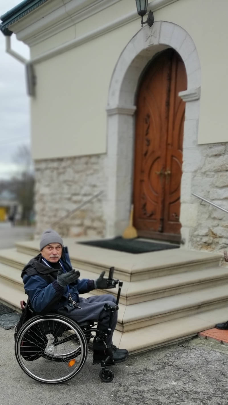 Чоловік на кріслі колісному перед сходами до церкви