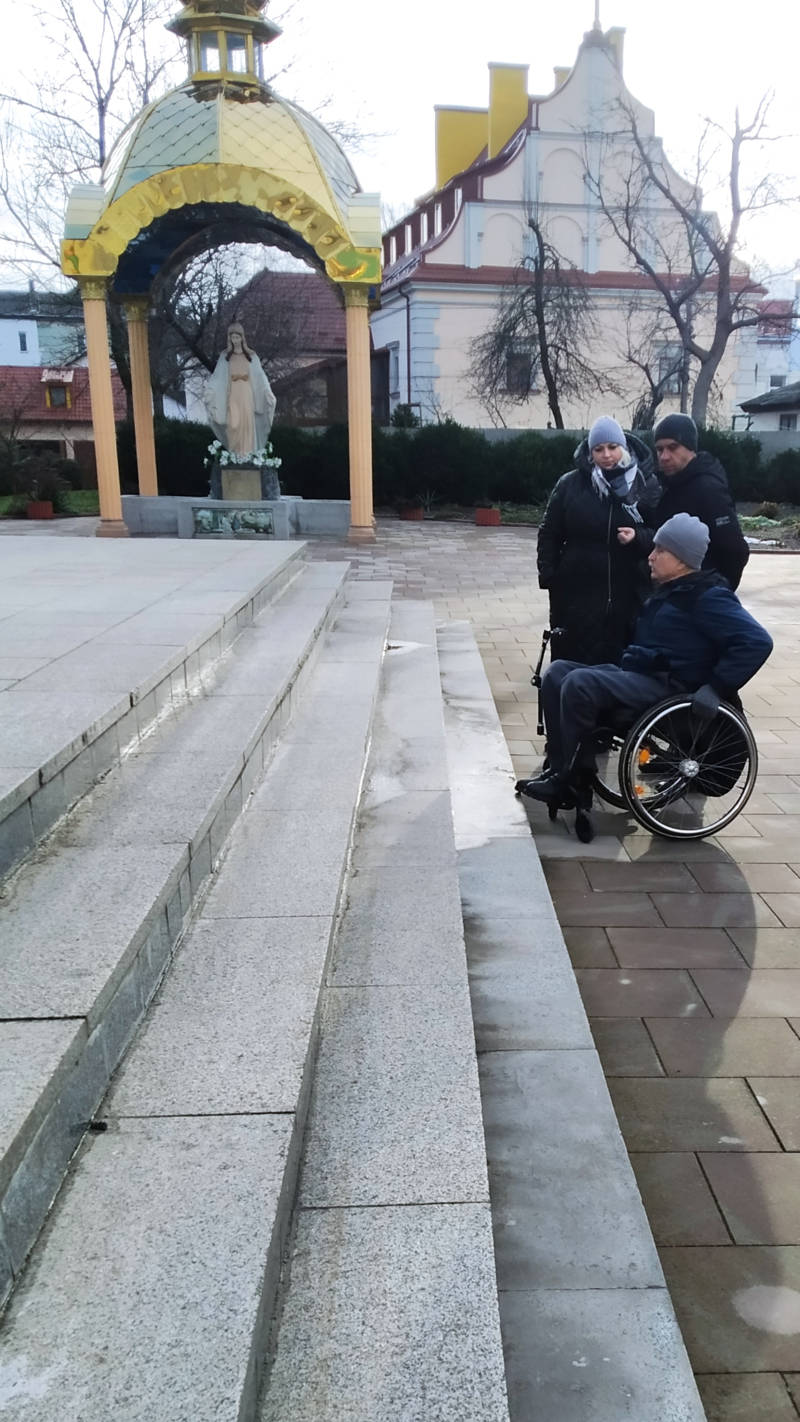 A man in a wheelchair in front of the stairs to the church